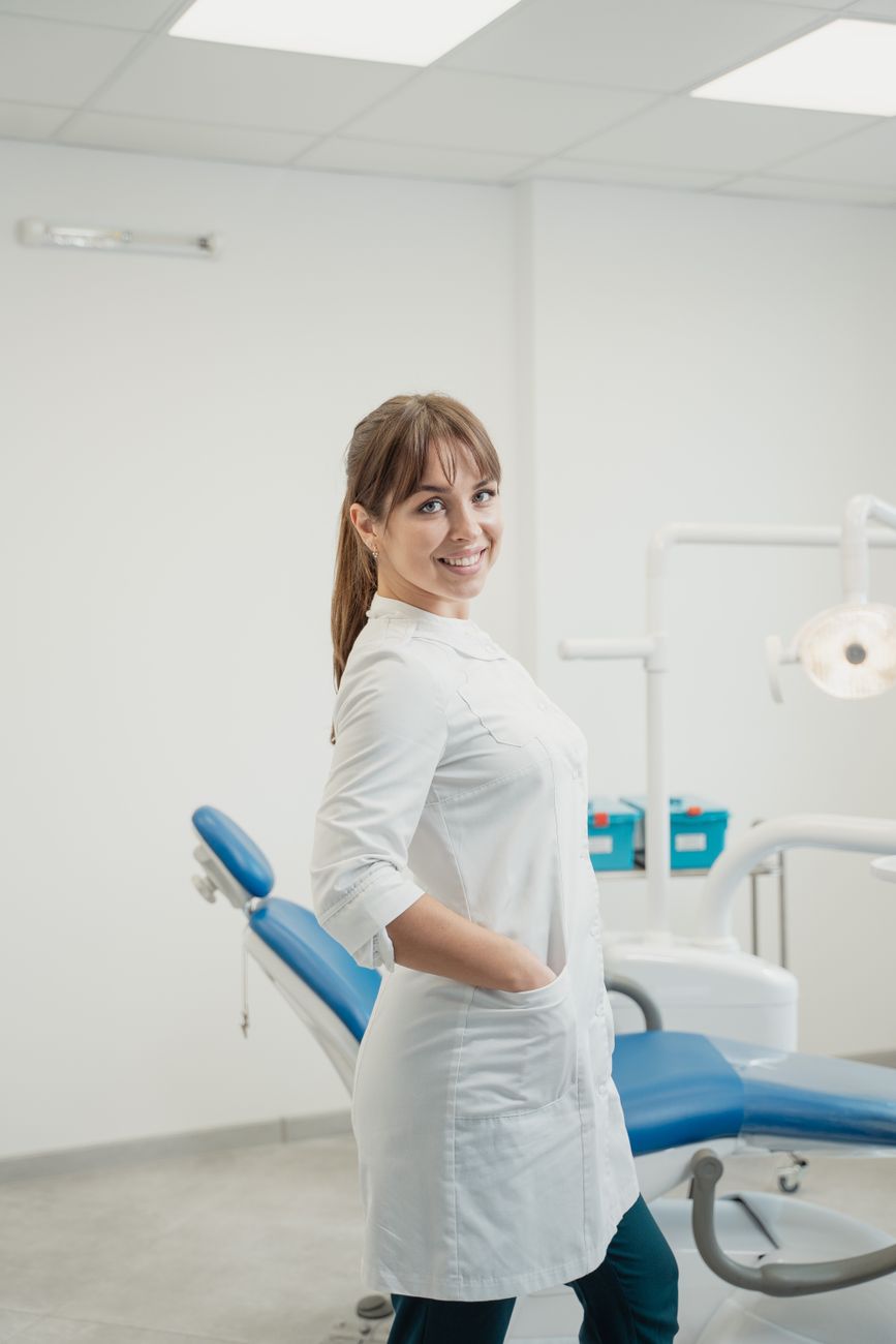 Profissional de saúde feminina sorrindo usando jaleco branco em ambiente clínico