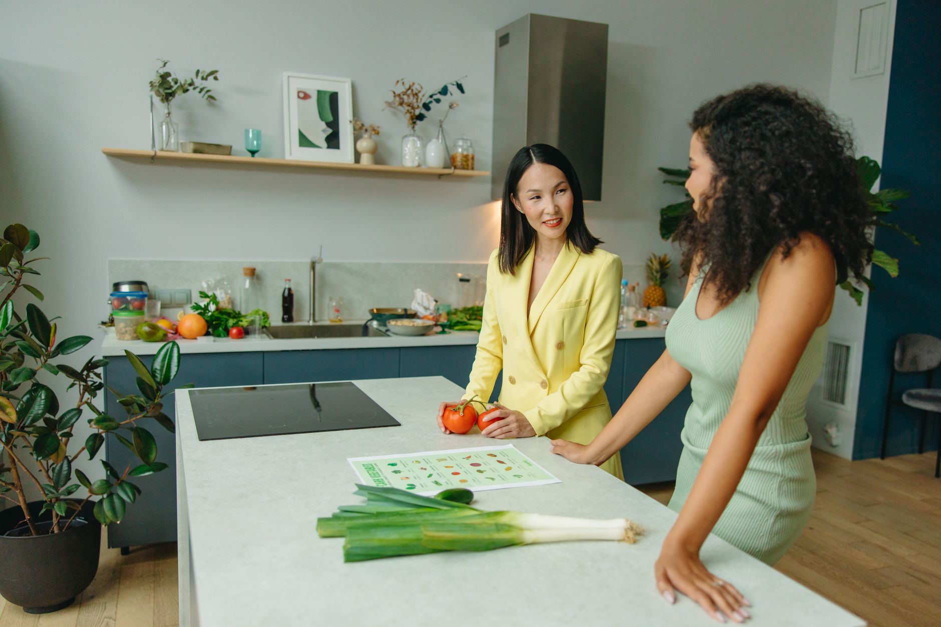 Duas mulheres discutindo uma dieta saudável em uma cozinha moderna com vegetais frescos.