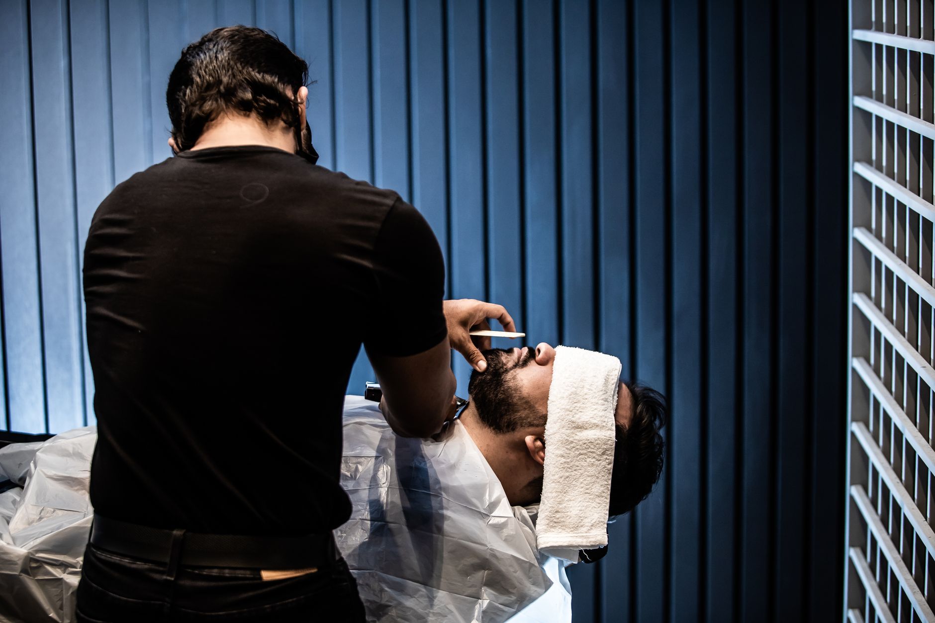 Barbeiro atendendo cliente em barbearia com ambiente profissional
