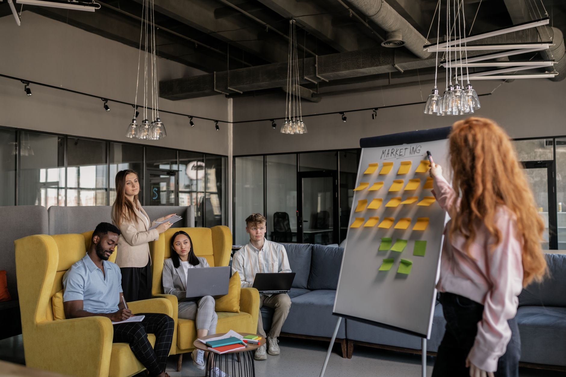 Empreendedor desenhando plano de crescimento no quadro branco com post-its e laptop ao lado