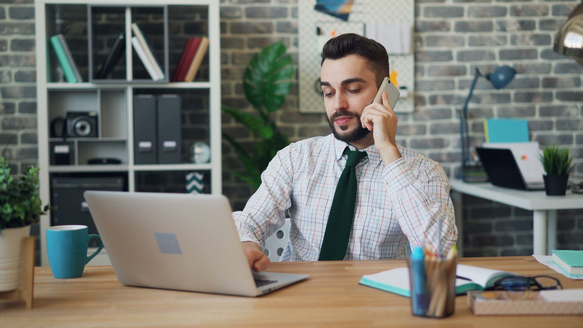 Dono de pequeno negócio revisando celular e laptop no balcão de trabalho